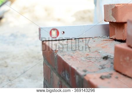 A Close-up On A Sprit Level Used To Level The Corner Brick Courses On A Mortar Bed While Bricklaying