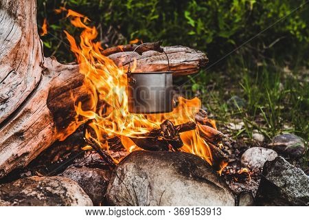 Kettle Hanging Over Fire. Cooking Food At Fire In Wild. Beautiful Big Log Burns In Bonfire Close-up.