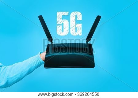 Black Wifi Router On Hand And 5g Inscription Over Blue Background