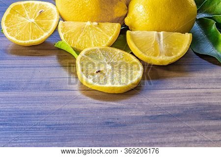 Top view of lemon and green leaves on wooden background