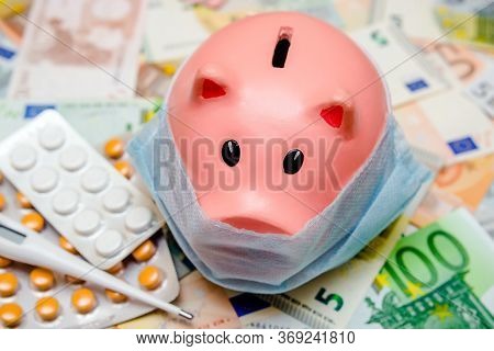 Piggy Bank In A Mask On A Background Of European Currency.the Concept Of Coronavrius Epidemic