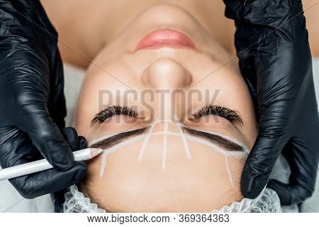 Markup With Pencil On Eyebrows Of Young Woman While Permanent Make Up, Top View.
