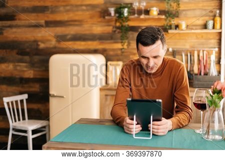 Young Cheerful Man Using Tablet Computer Having Online Video Chat With Friends While Sitting At The 