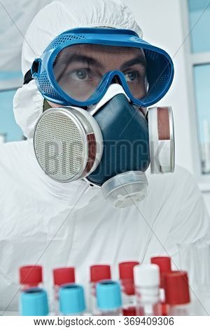 COVID-19. Doctor, microbiologist, scientist in a protective suit, makes a research on blood samples of infected people in the laboratory. Coronavirus test.