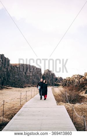 A Guy And A Girl Are Walking Down The Road In The Silfra Fault, In The Tingvedlir Valley.