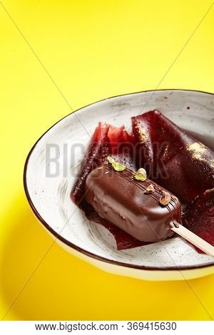 Chocolate mousse dessert close up. Luxury restaurant sweet course side view. Ice cream served with pastila in deep craft plate. Fancy confectionery dish with jellied fruit sweetmeat. Sweet food