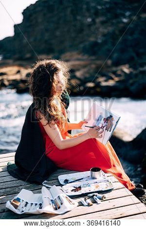 The Girl Artist Paints A Picture In The Album With Watercolors. Near Ehsaraurfoss Waterfall, Ehsarau