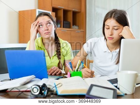 Dreary Teenage Student Girls Study In The Home With Books And Computers