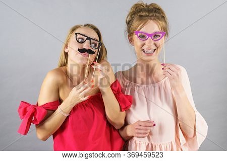 Happy Two Women Holding Paper Decoration Photo Booth Mask Glasses And Moustache On Stick, Having Fun