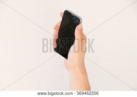 Broken Glass Of Smartphone Screen In The Hand Of A Young Man, White Background.