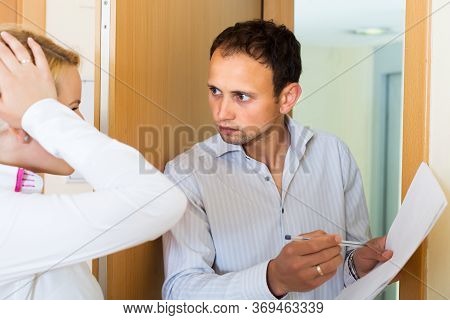 Businessman Trying To Collect Money From Unhappy Housewife At Home Door