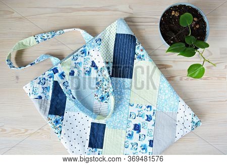 Quilted Patchwork Tote Bag And Green House Plant In Bowl On Wooden Table