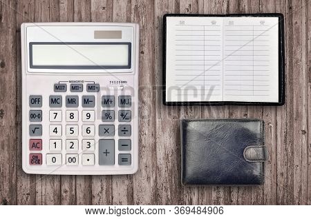 Office Flat Lay Composition With Calculator, Address Book And Black Purse On Brown Wooden Table Back
