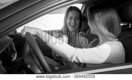 Black And White Portrait Of Two Laughing Girls Singing And Smiling Hile Driving A Car