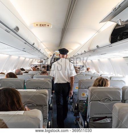 Interior Of Commercial Airplane With Flight Attandant Serving Passengers On Seats During Flight. Ste