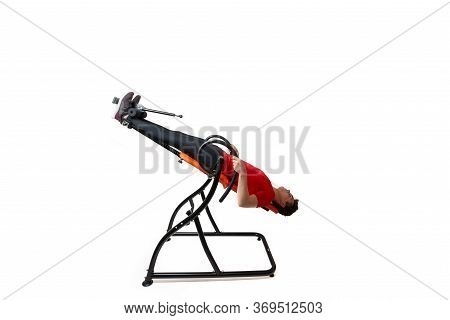 Man Doing Exercise On Inversion Table For His Back Pain, Isolated On White