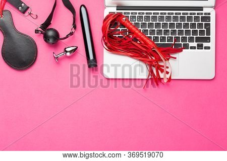 Adult Webcam And Virtual Sex Chat Concept. Laptop With Whip, Dildo Vibrator, Buttplug And Gag On Red