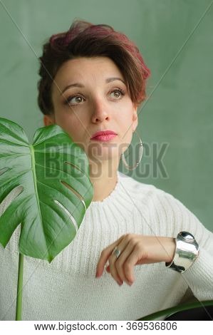 Beauty Portrait Of Sensual Brunette Girl With Dark Pink Hair And White Sweater Holding A Green Sprin