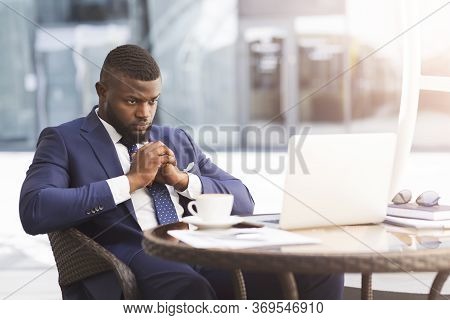 Coronacrisis And Bankruptcy. Thoughtful Black Businessman Sitting At Laptop Thinking How To Save Bus