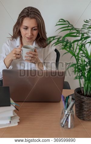 Woman Working On Laptop At Home Office While Drinling Coffee. Web Conection