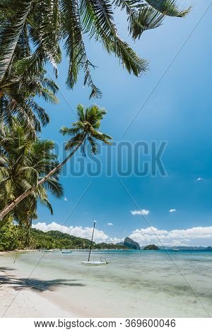 Palm Trees Of Corong Corong Beach With Traditional Boats And Blue Sky In El Nido, Palawan Island, Ph