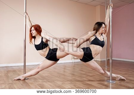 Two Young Girls Train Pole Dance And Do A Synchronous Trick Together, Gymnasts Hang On A Pylon In Th
