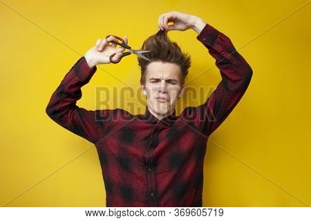 Sad Guy With A Funny Hairstyle Cuts His Long Hair And Cries On A Yellow Isolated Background, Unhappy