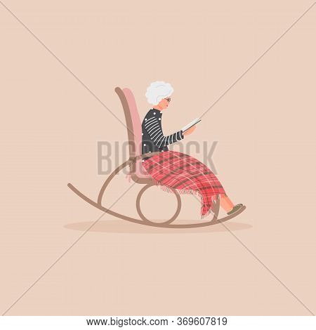 Elderly Cute Woman Is Sitting In A Rocking Chair.old Lady Covered Her Feet With Checked Woollen Plai