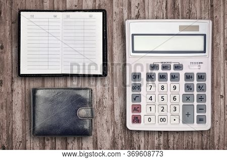 Office Flat Lay Composition With Calculator, Address Book And Black Purse On Brown Wooden Table Back