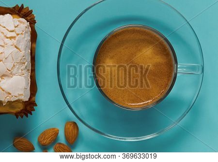 A Glass Cup Of Black Coffee With Merinque Cake And Almond
