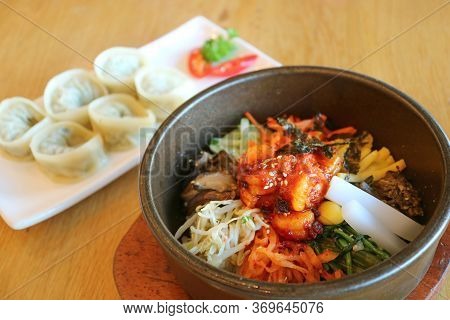 Mouthwatering Bibimbap Or Korean Mixed Rice Bowl With Blurry Mandu Dumplings In Background
