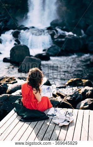 The Girl Artist Paints A Picture In The Album With Watercolors. Near Ehsaraurfoss Waterfall, Ehsarau
