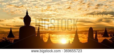 Silhouette Of Buddha On Golden Temple Sunset Background. Travel Attraction In Thailand.