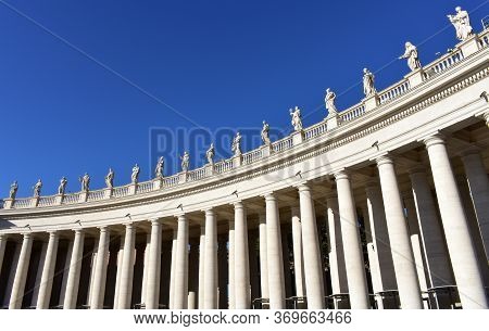 Berninis Colonnade And Statues At St. Peters Square With Blue Sky. Vatican City, Rome, Italy.