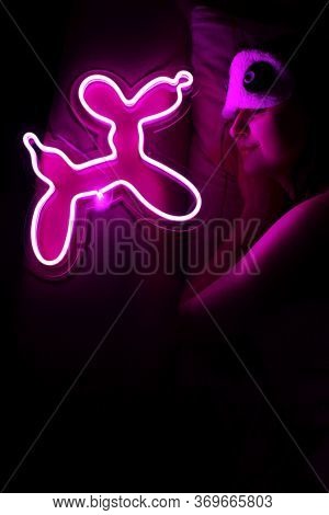 A Beautiful Girl Is Sleeping In A Sleep Blindfold With A Purple Neon Sign Dog. Good Night. Trendy St