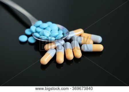 Spoon With Pills, Drugs In Capsules And Tablets On A Dark Glass Table. Concept Of Pharmacy, Antibiot
