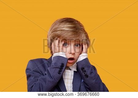 The Cute Blond Boy Holds On To His Head With Fright.