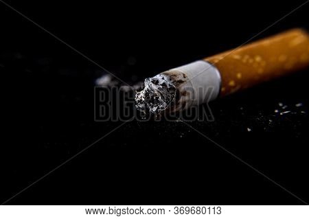 Cigarette Butt On A Dark Black Background