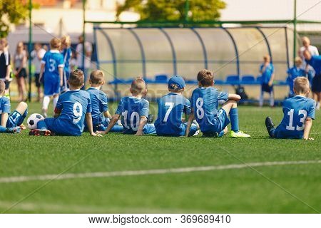 Youth Football Team Members Sitting Together On The Field. Kids Playing Soccer Tourament Game. Child