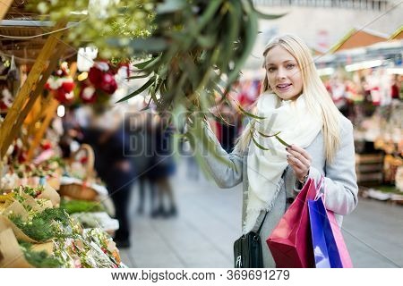 Portrait Of Happy Female Customer Choosing Eucalyptus Decorations For Christmas Outdoor