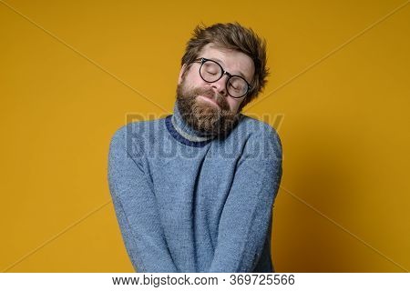 Shy Caucasian Man With A Shaggy Hairstyle And Beard Modestly Folded Hands And Closed Eyes, With A Cu