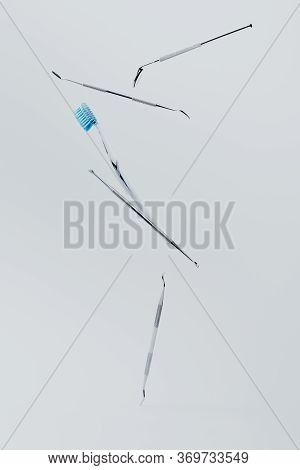 Dental Instrumens And Toothbrush Levitating On Grey Background