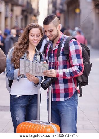 Positive Man And Woman With Luggage Walking Through City Street