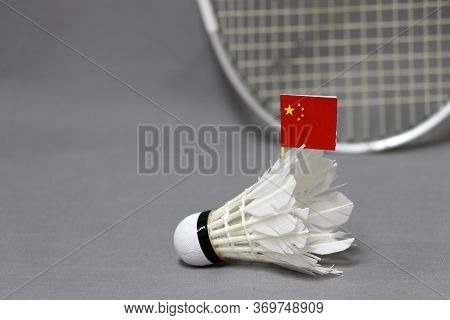 Mini China Flag Stick On The White Shuttlecock On The Grey Background And Out Focus Badminton Racket