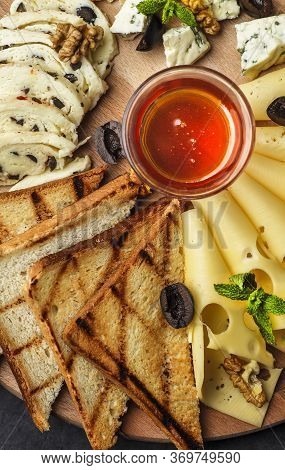 Cheese Plate: Parmesan, Cheddar, Gouda, Mozzarella And Other With Basil On Wooden Board On Dark Back