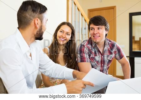 Couple And Salesman Talking Cheerfully About Purchase At Home