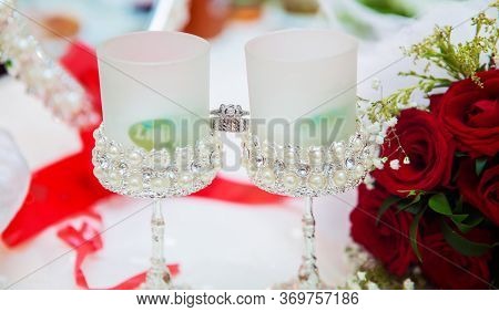 Wedding Bouquet Of Red Flowers. There Are Drops Of Water On The Roses . Wedding Rings Are Placed On 