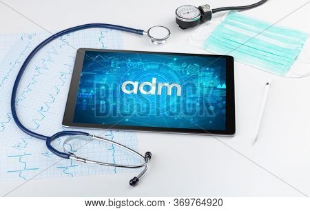 Close-up view of a tablet pc with adm abbreviation, medical concept