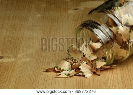 Pencil Shaving Spilling Out A Glass Jar And Onto A Wooden Table