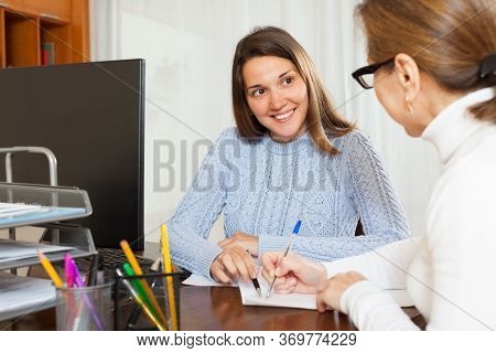 Smiling Young Woman Talking With Employee At The Table In Office